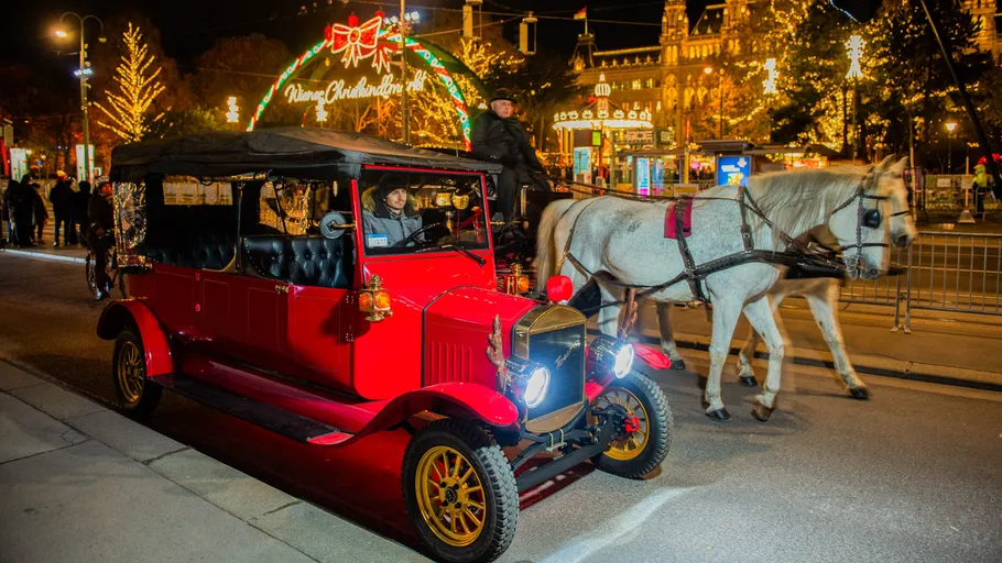 Carriage and car on festive city street.