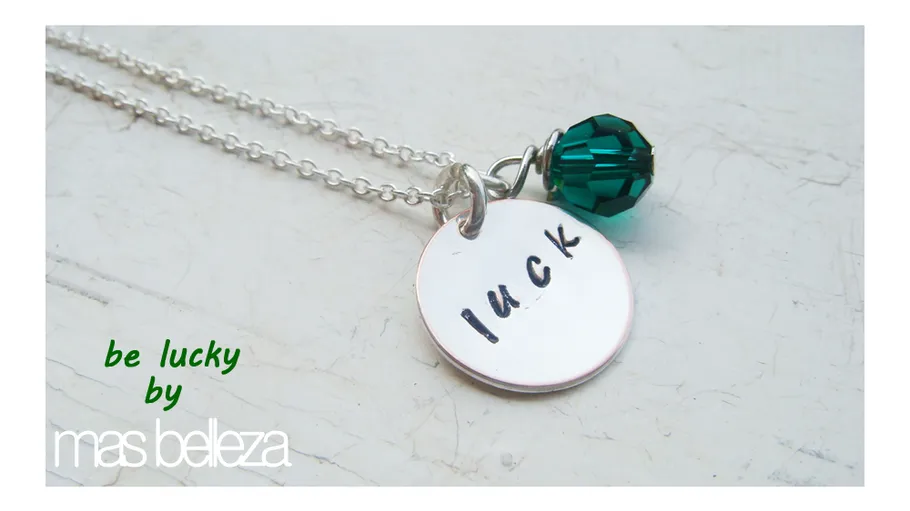 Necklace with charm and green bead on table.