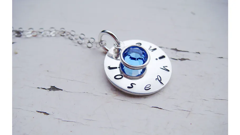 Silver necklace with round blue gem pendant.