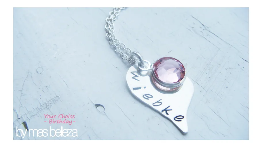 Herzhalskette mit rosa Edelstein auf Oberfläche.