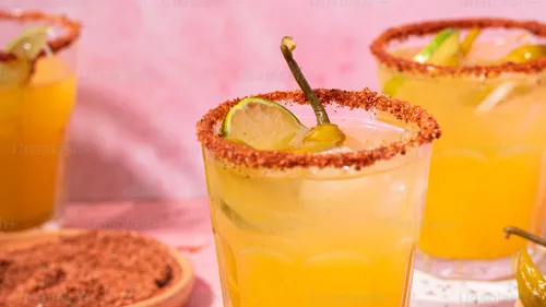 Gelbe Cocktails mit Chilirim, rosa Hintergrund.