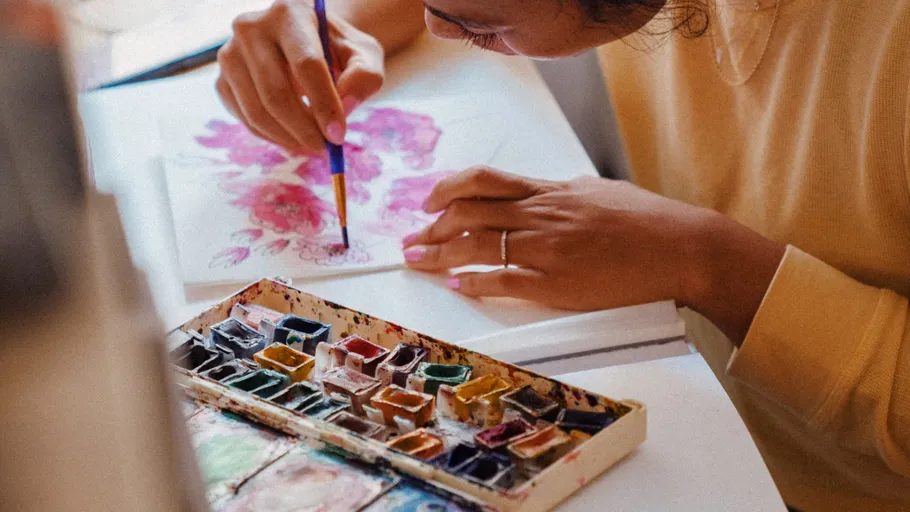 Person painting with watercolors on paper.