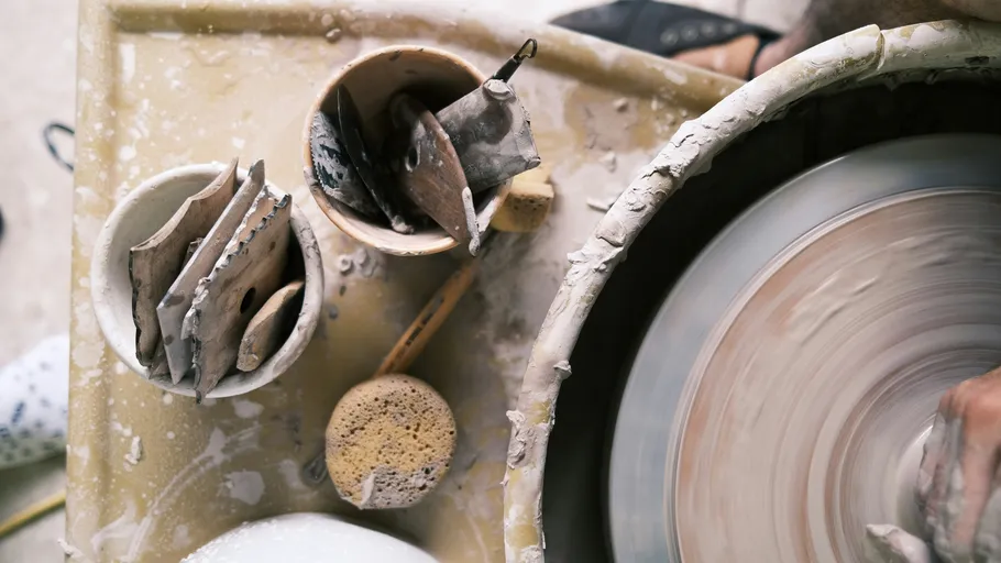 Pottery wheel with clay tools and hands.