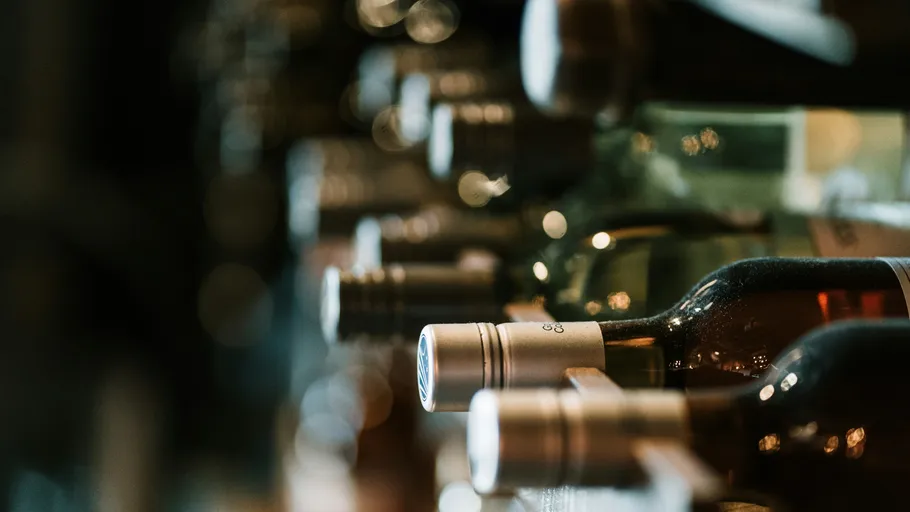 Wine bottles stored on a shelf in a cellar.