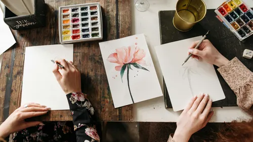 Artists sketching and painting on wooden table.