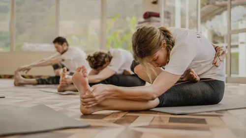 Personen machen Yoga-Dehnungen im Studio.