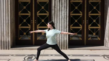 Frau übt Yoga vor verzierten Türen.