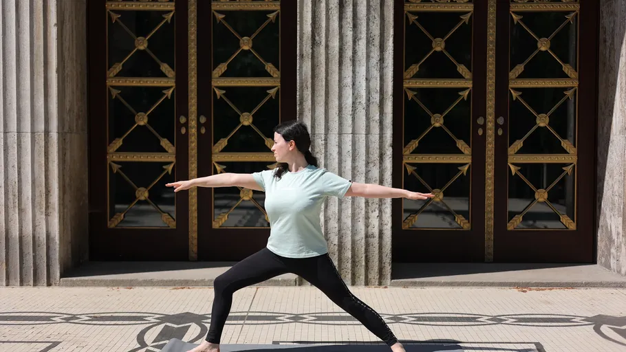 Woman practicing yoga outdoors by ornate doors.
