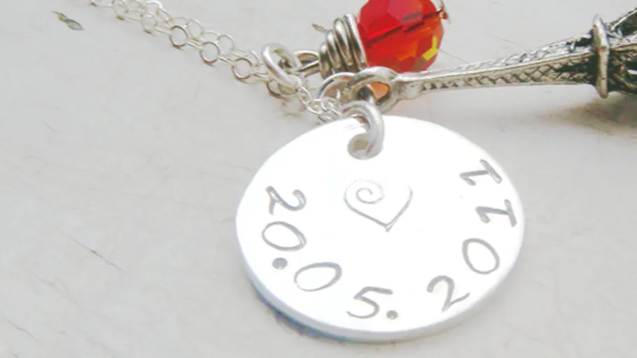 Silver necklace with engraved date and Eiffel Tower.