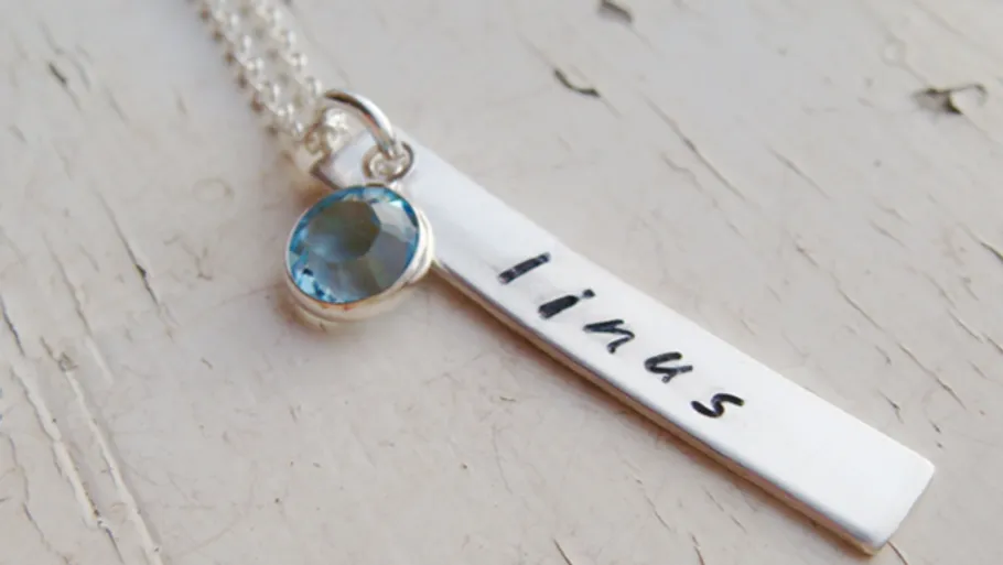 Silberne Halskette mit blauem Edelstein und Name.