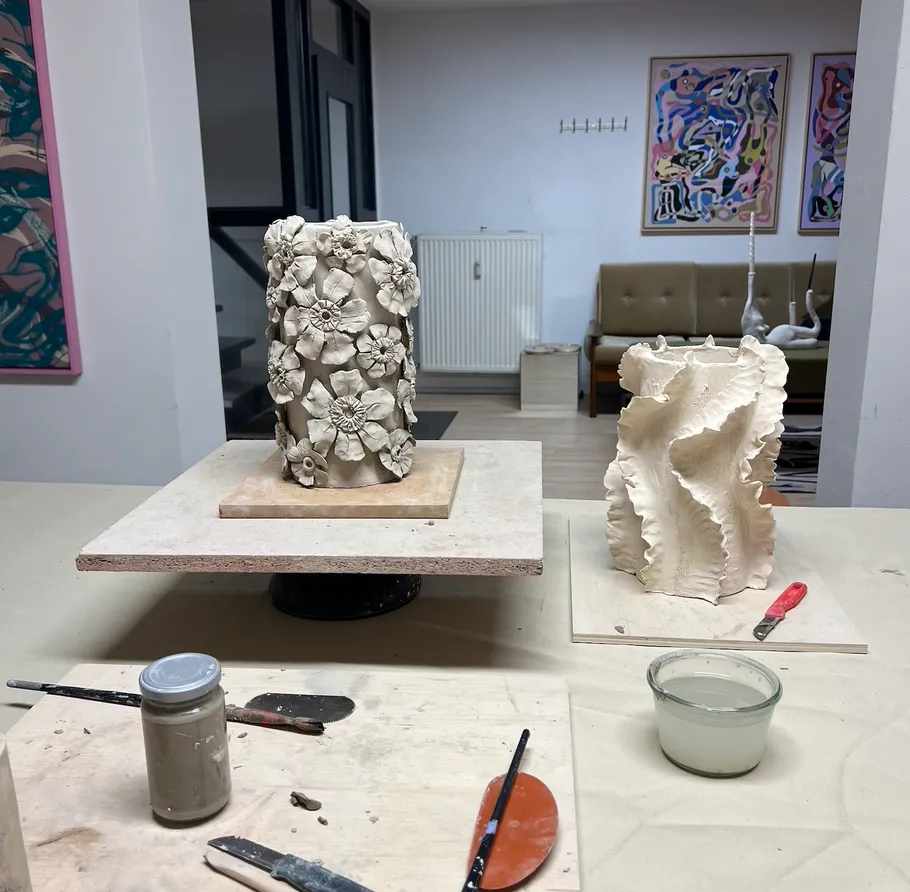 Clay sculptures on tables in art studio.