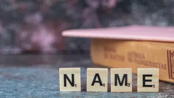 Scrabble-Steine buchstabieren NAME neben Buch.