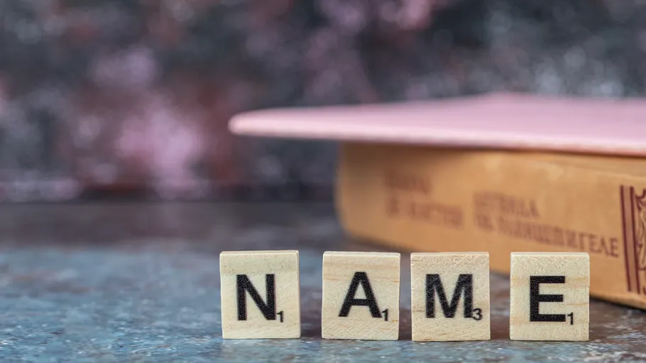 Scrabble tiles spell NAME beside book.