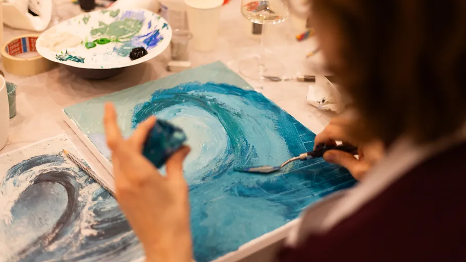Person painting waves on a canvas.