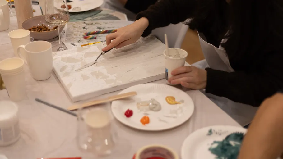 Person painting on canvas at a table.