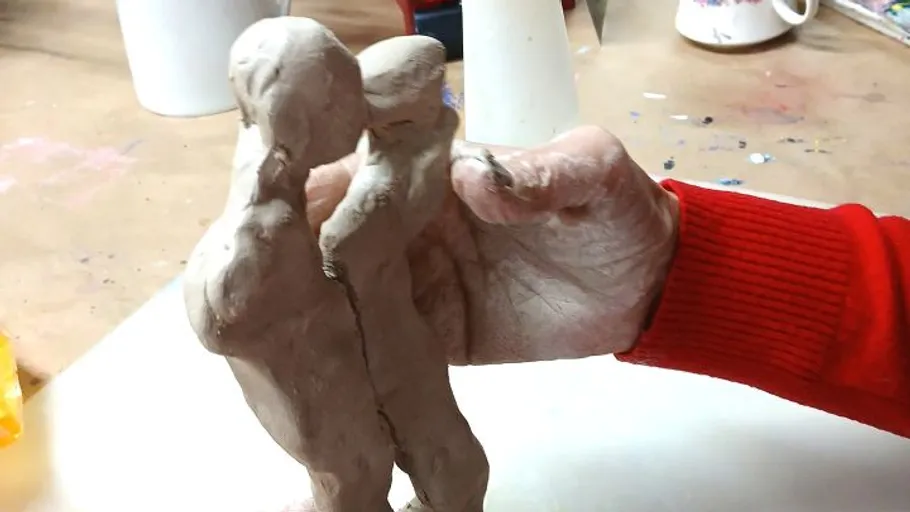 Person molds clay figures on a table.