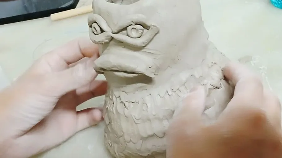 Hände formen eine Ton-Vogelfigur.