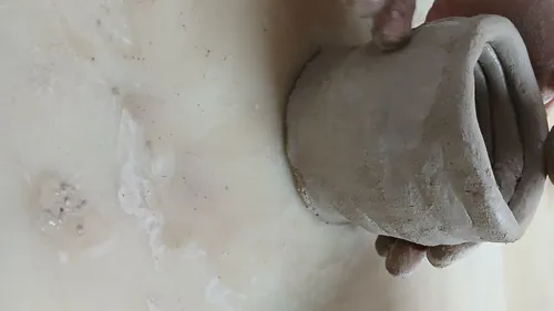 Hands sculpting clay pot on table.