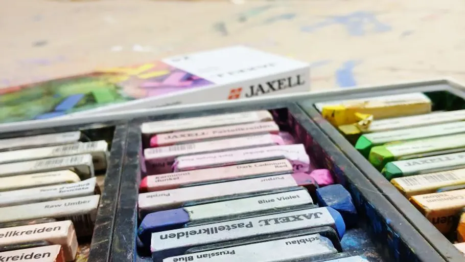 Bunte Pastelle in offener Schachtel auf Tisch.