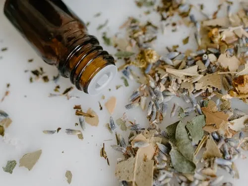 Braune Flasche liegt auf Kräutern und Blüten.