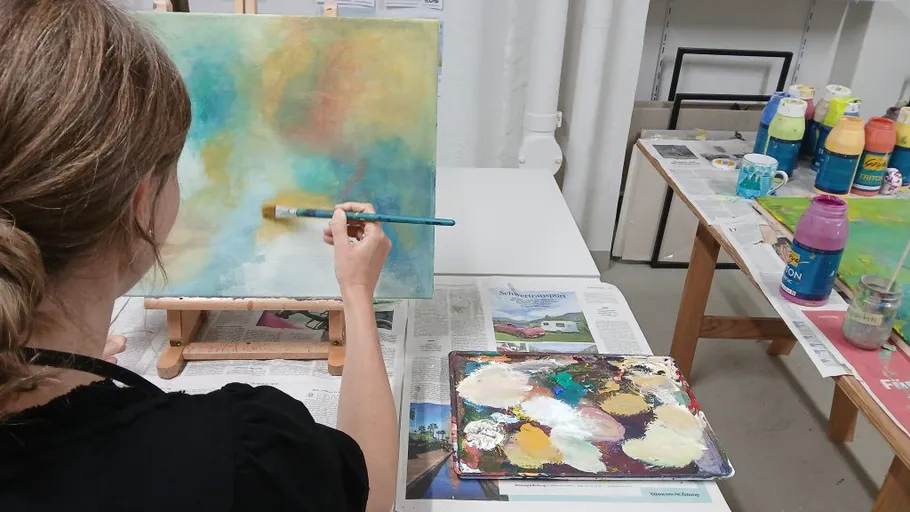 Person painting abstract canvas with brush indoors.