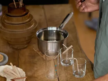Wax is poured into pots for candles. Environment: table.