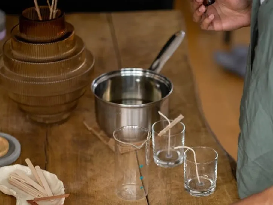 Wax is poured into pots for candles. Environment: table.