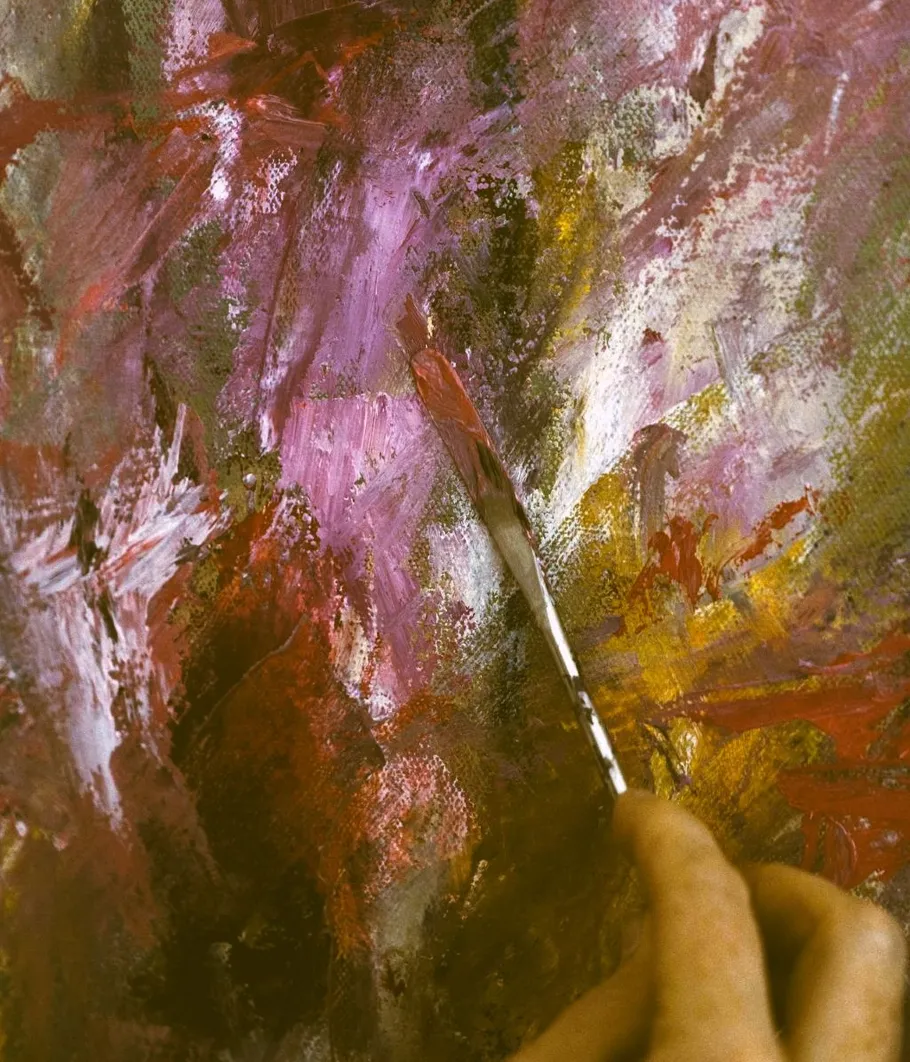 Paintbrush applying colors on abstract canvas.