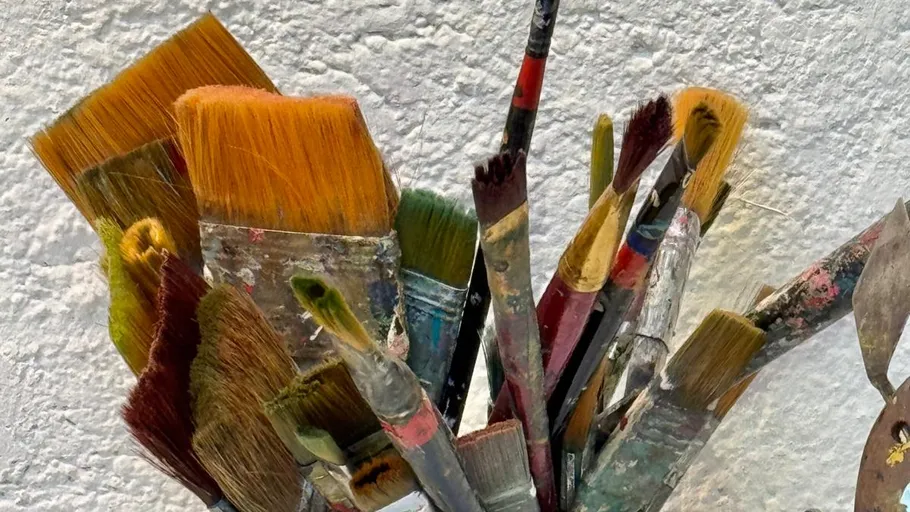 Assorted paintbrushes against a white wall.