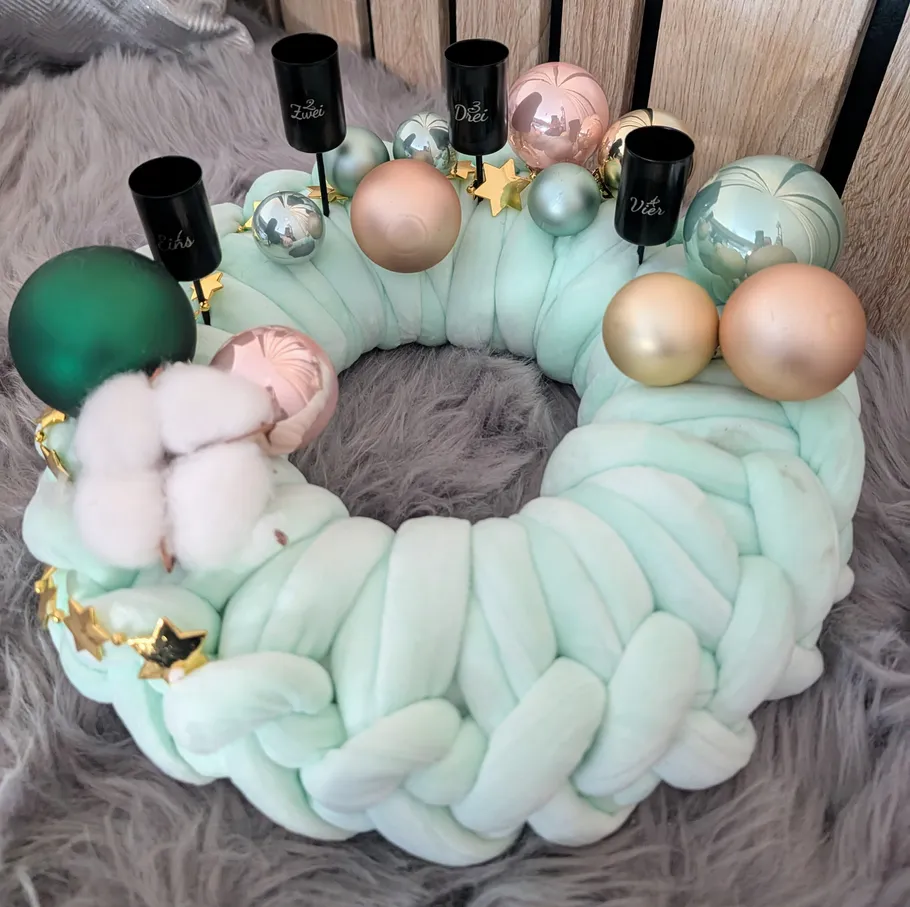 Braided wreath with ornaments on a fluffy surface.