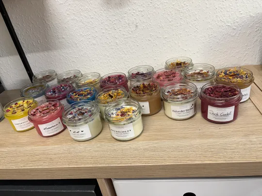 Colorful scented candles on wooden shelf.