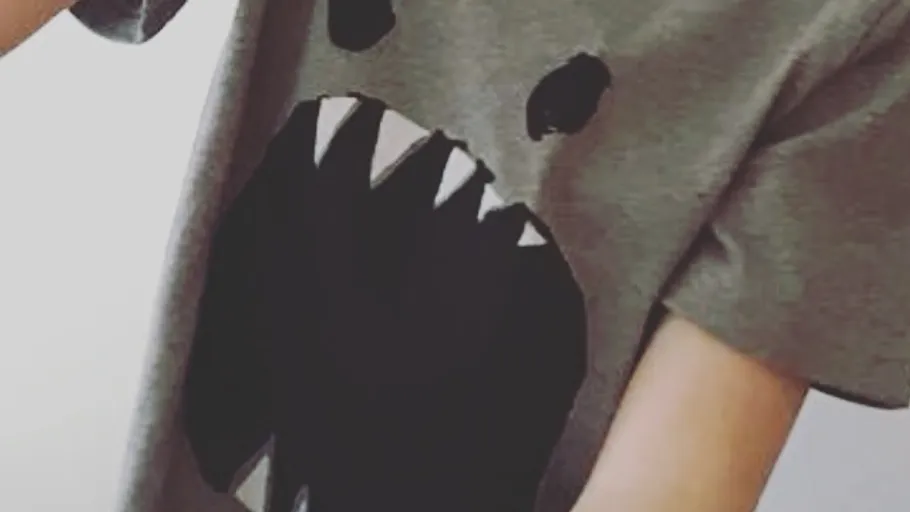 Graues T-Shirt mit schwarzem Monster Gesicht Design.