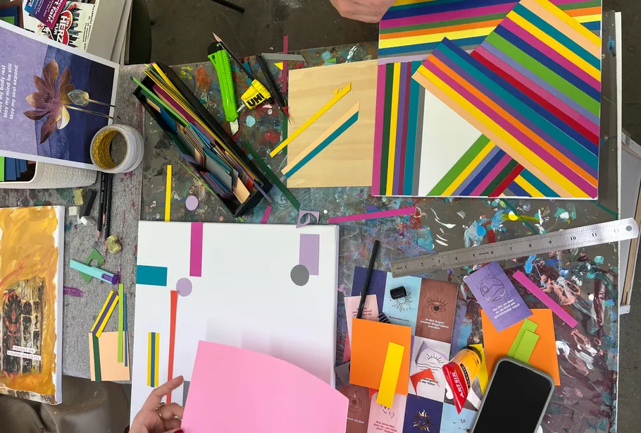 Kunstzubehör und bunte geometrische Kunstwerke auf Tischen.