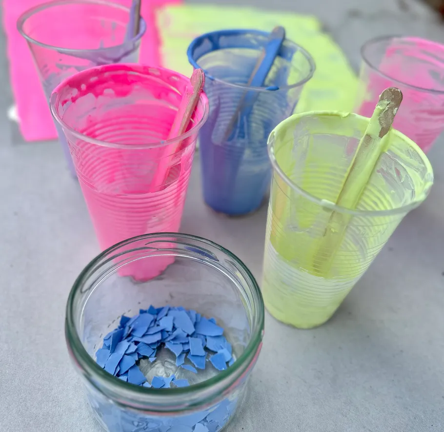 Colorful paint cups with sticks on table.