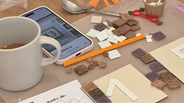 Bastelmaterialien mit Handy und Kaffeetasse.