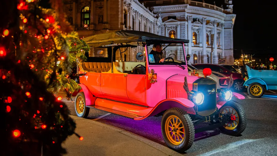 Colorful vintage car driving near ornate building.