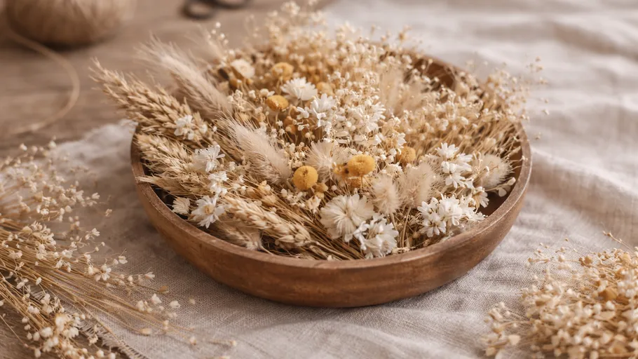 Dried flowers arranged in a wooden bowl.