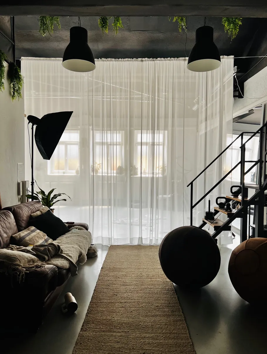Living room with sofa, plants, and curtains.