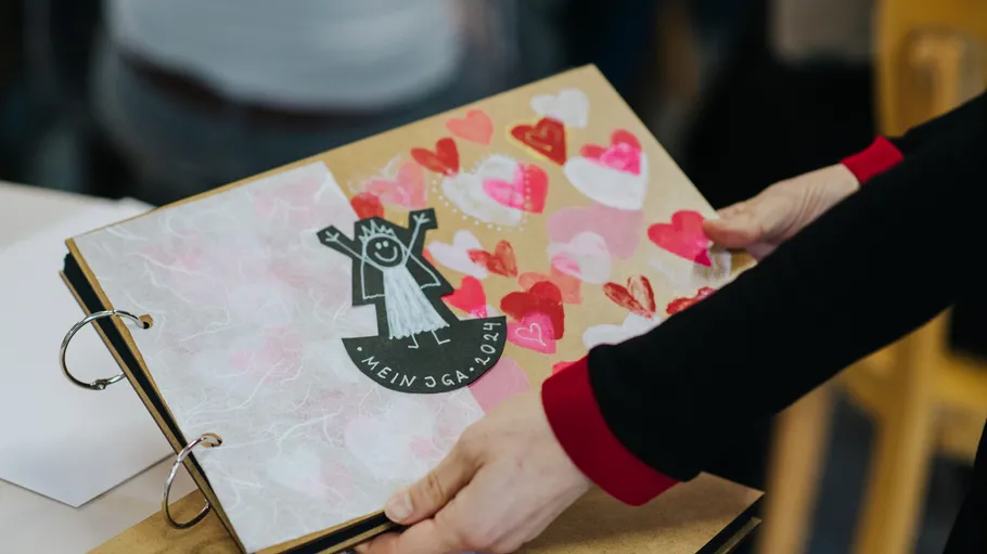 Person hält Scrapbook mit Herzdekorationen.