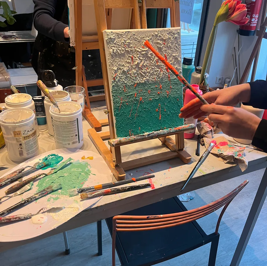 Person painting textured canvas in art studio.