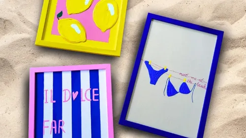 Three colorful framed artworks on sandy surface.