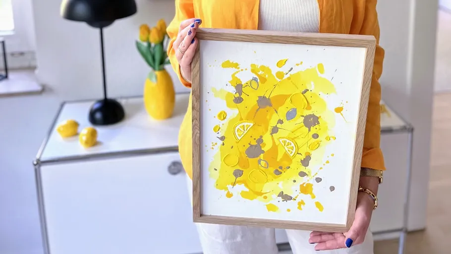 Person hält gelbes abstraktes Kunstwerk im Raum.