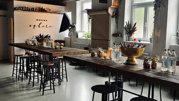 Wooden tables with stools, bottles, and decorations in studio.