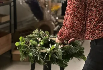 Person arranging a wreath on a table.