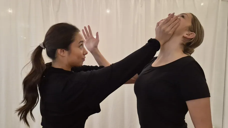 Two people in self-defense demonstration indoors.
