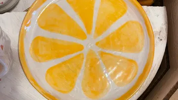 Orangenfarbener Keramikteller mit Zitrusdesign.