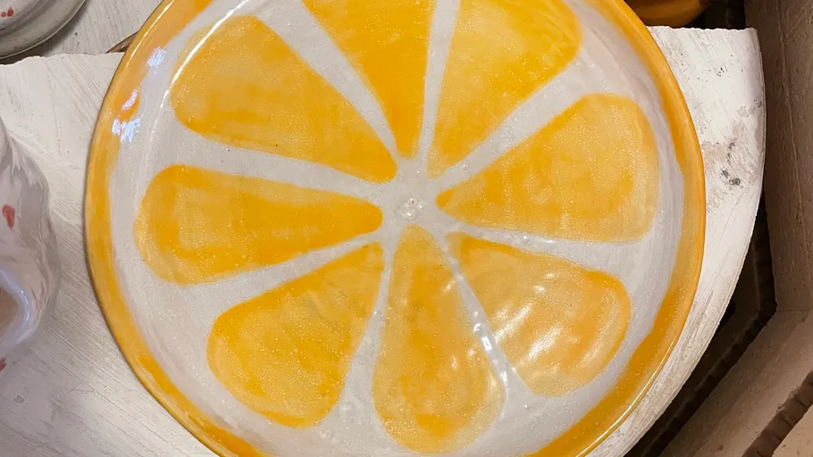 Orangenfarbener Keramikteller mit Zitrusdesign.