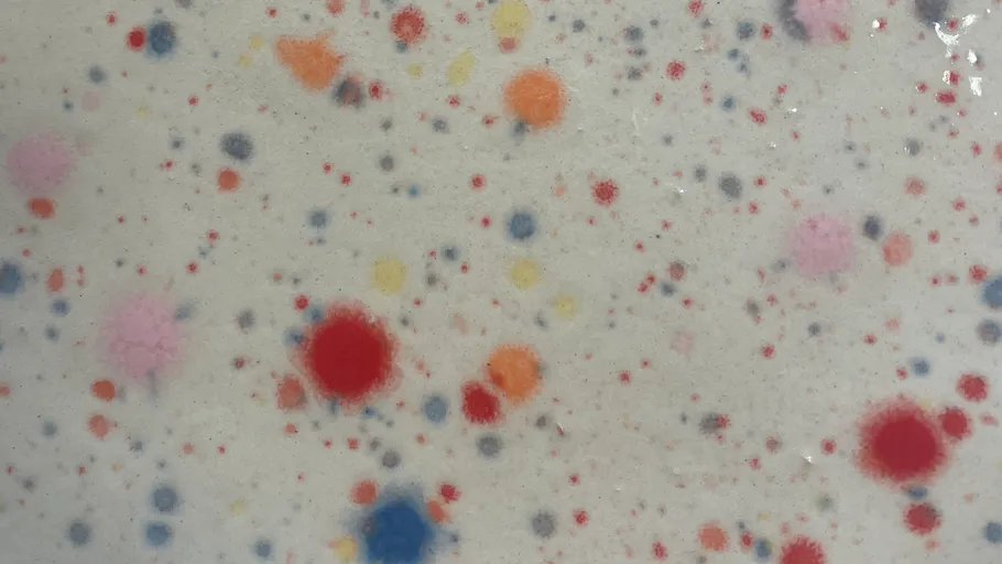 Colorful paint splatters on white surface.