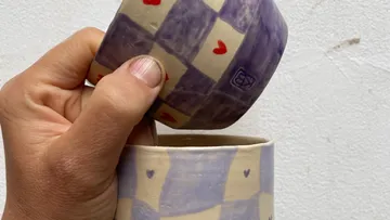 Hand hält gemusterte Keramikschale und Becher.
