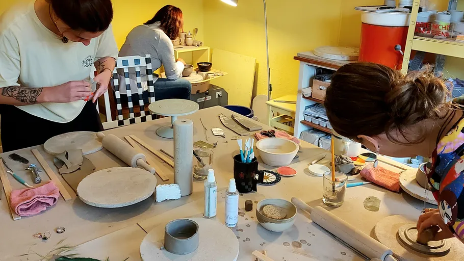 Three people working on pottery in studio.